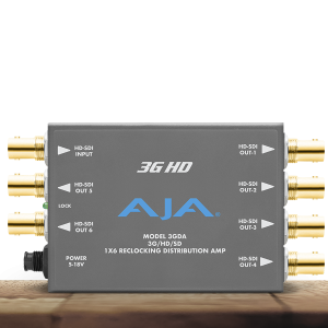 Amplificador distribuidor AJA 3GDA para vídeo profesional en chasis metálico gris, con siete conectores BNC dorados de alta calidad, LED de bloqueo de señal y entrada de alimentación circular.