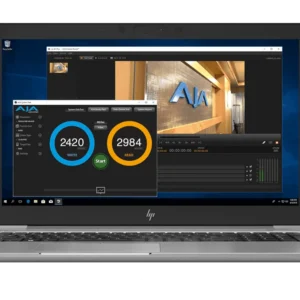 Pantalla de ordenador portátil con la interfaz de AJA System Test, mostrando resultados de velocidad de lectura y escritura de disco de alto rendimiento (2420 MB/s escritura y 2984 MB/s lectura) para flujos de trabajo en 4K.
