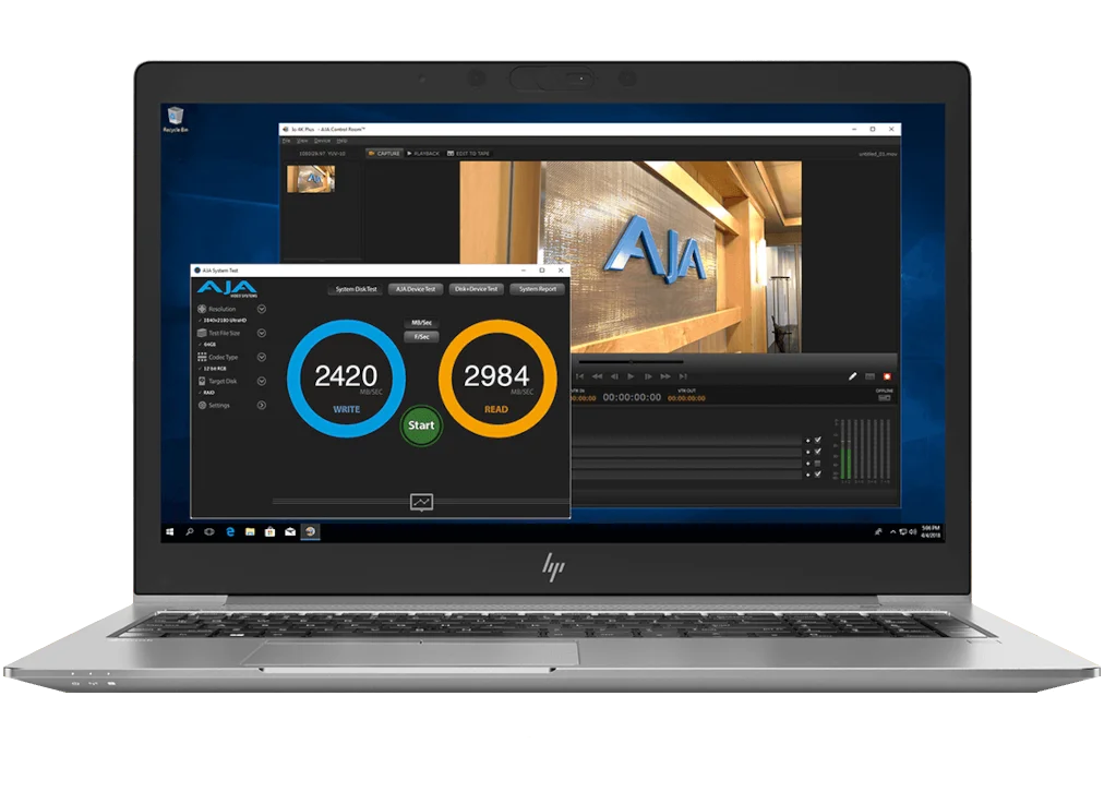 Pantalla de ordenador portátil con la interfaz de AJA System Test, mostrando resultados de velocidad de lectura y escritura de disco de alto rendimiento (2420 MB/s escritura y 2984 MB/s lectura) para flujos de trabajo en 4K.